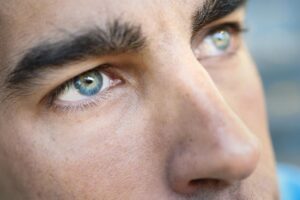Close-up of a man’s face highlighting his striking blue eyes and facial features.