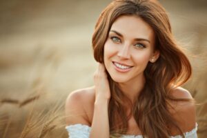 A woman with long, flowing hair stands in a golden field, gently holding her neck , exuding a calm and serene vibe.