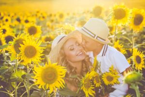 A happy moment in a sunflower field, with bright yellow flowers surrounding mother and son in sun hats enjoying the warm sunlight.