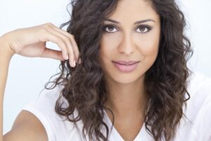 A woman with flowing curly hair poses for the camera, exuding confidence and charm.