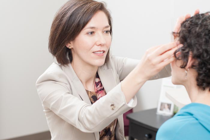 Dr. Vivian Schiedler checking eye of a lady patient .