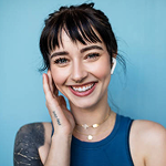 Stock image of a smiling woman touching her cheek with right hand .
