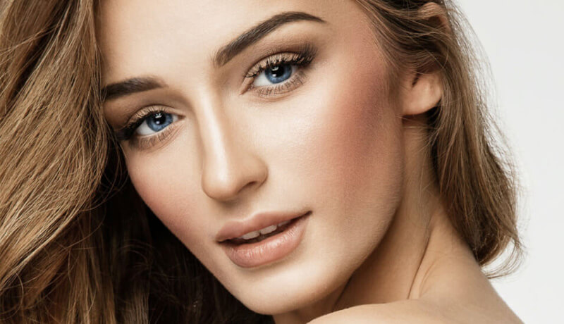 A woman with long hair and striking blue eyes gazes thoughtfully into the distance.