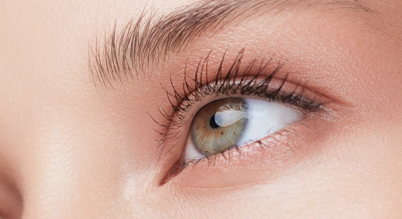 A close-up of a person's hand gently touching side of an eye.
